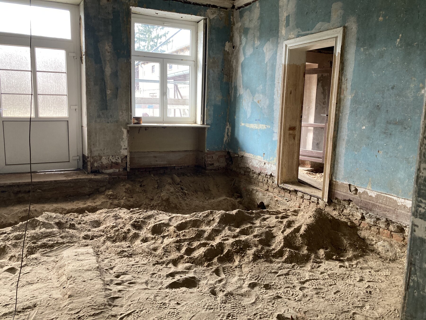 Bauphase mit freigelegtem Boden und alten Wandflaechen