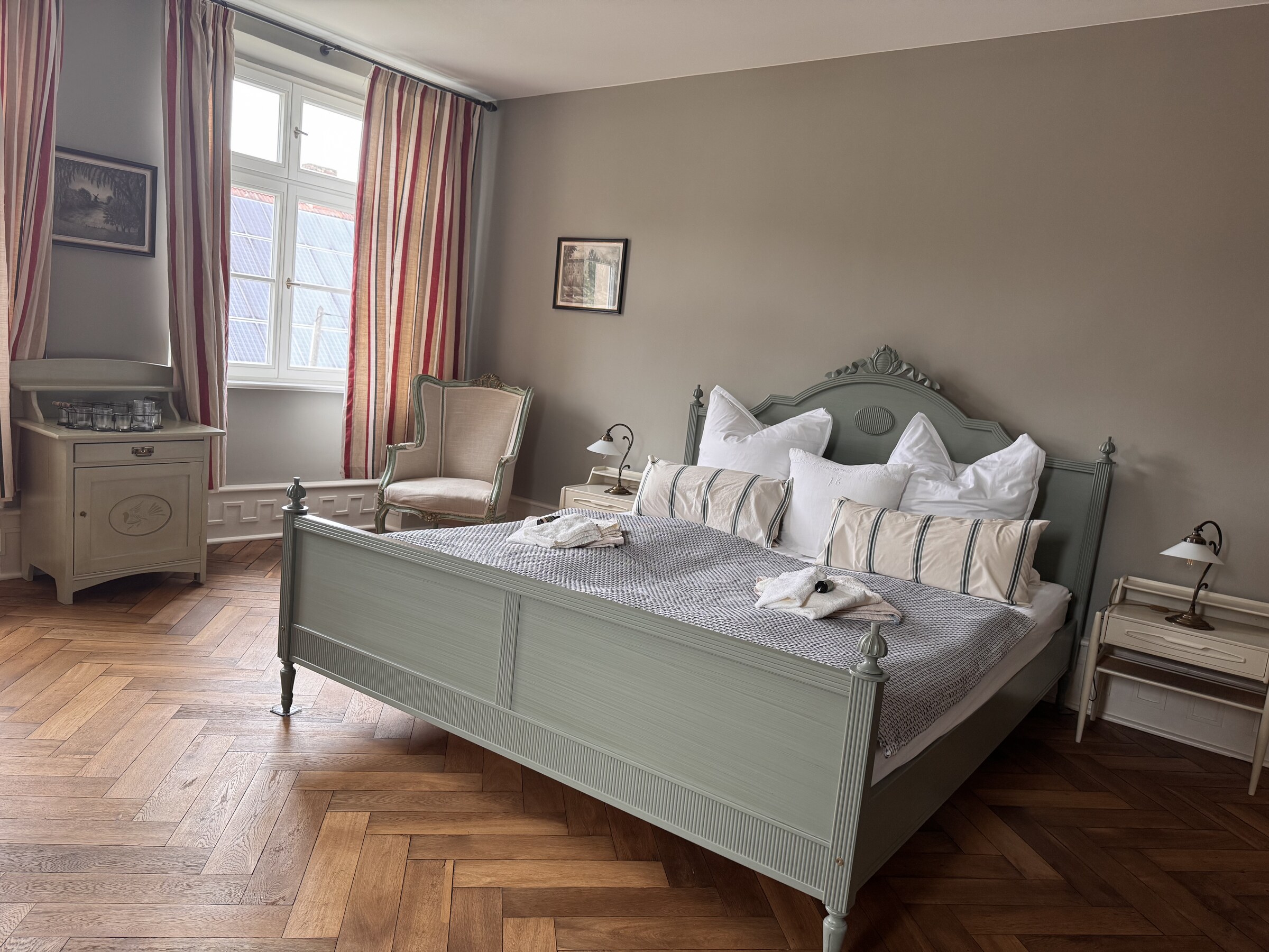 Schlafzimmer mit grünem Holzbett und Fischgrätparkett