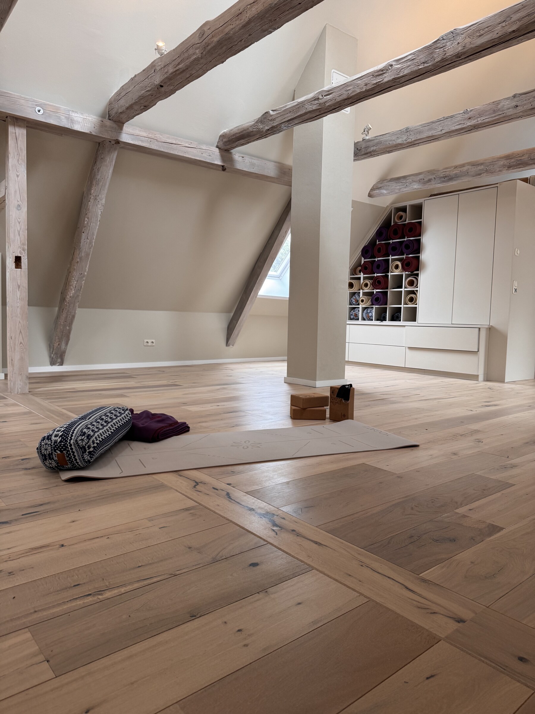Yoga-Raum mit Mattenregal und Holzgebälk